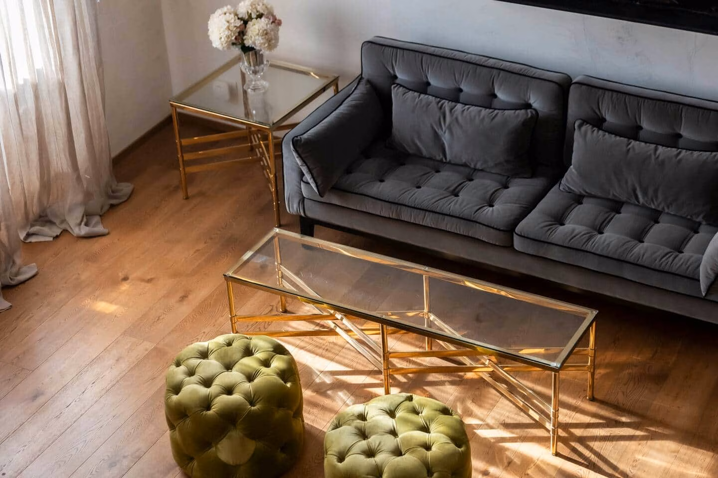 At Home — angolo relax con divano in velluto grigio capitonné, tavolino in ottone e vetro e pouf in velluto verde oliva