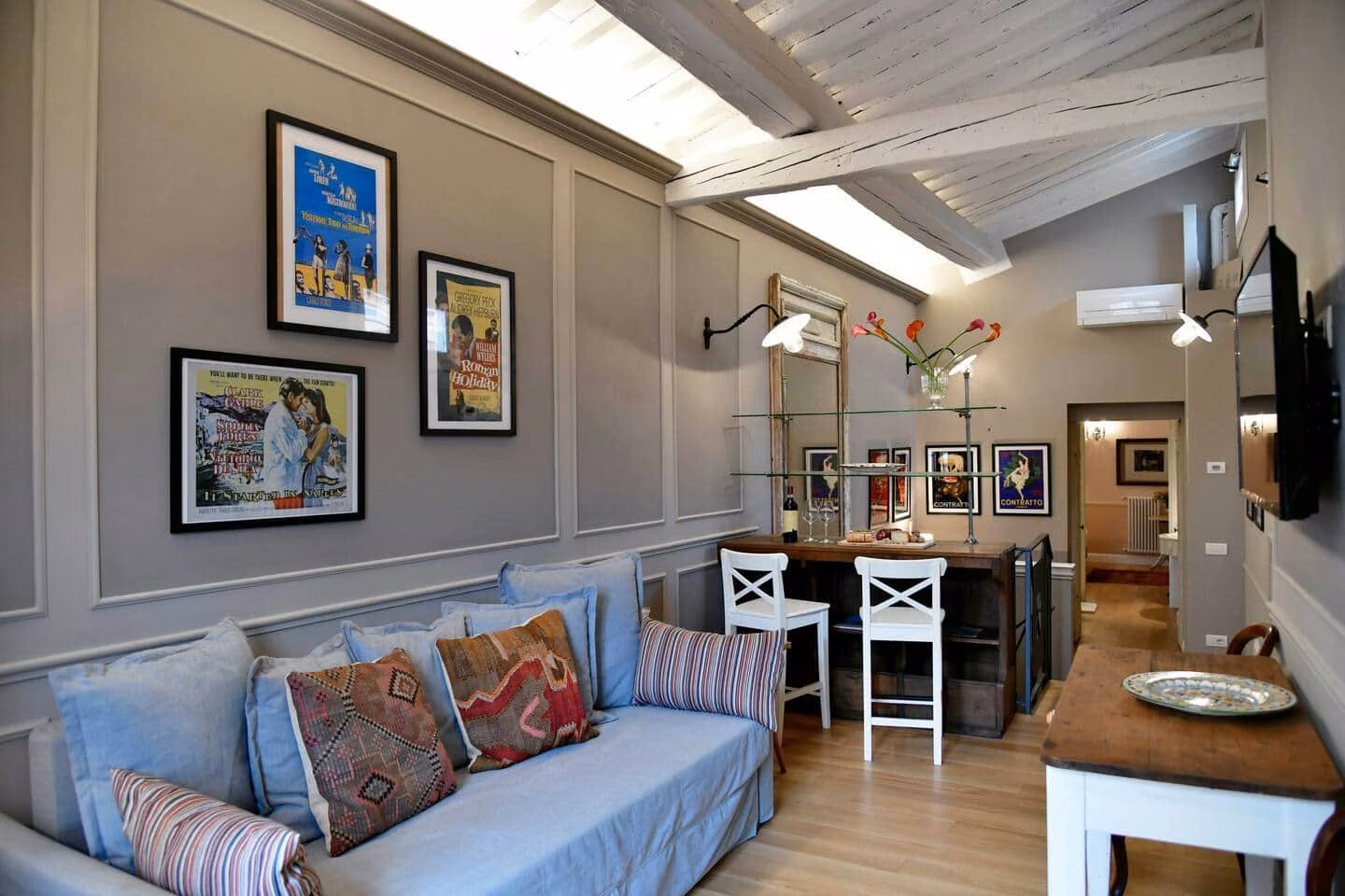Il Bue Terrace Apartment — soggiorno con divano blu e manifesti vintage del cinema italiano