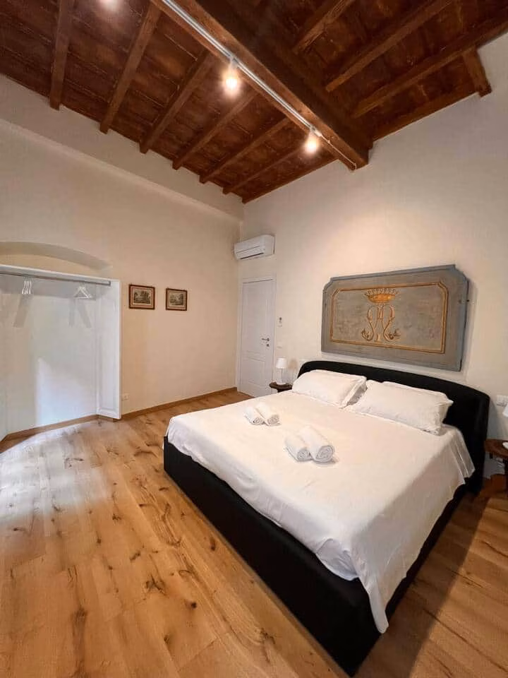 Sprone Left — camera matrimoniale con soffitto a travi a vista, pavimento in rovere e testiera dipinta d'epoca
