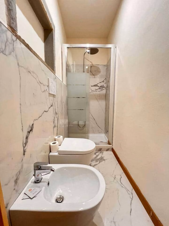 Sprone Left — bagno rivestito in marmo venato chiaro con doccia walk-in a pioggia